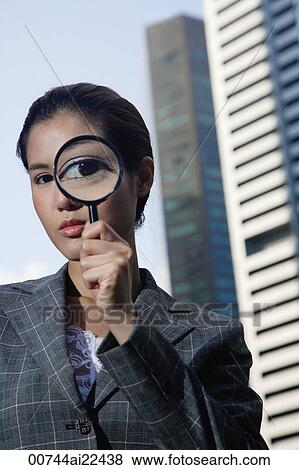 Stock Photo - A woman looks at the camera through a magnifying glass. Fotosearch