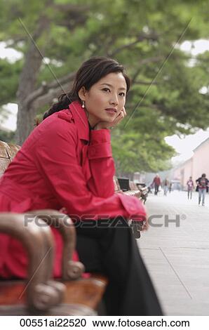 Stock Image - A woman looks into the distance as she sits down. Fotosearch