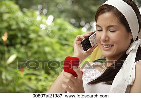 A young woman talks on her cellphone as she looks in a jewellery box View Large Photo Image Stock Photo - A young woman talks on her cellphone as she looks in a jewellery box. Fotosearch