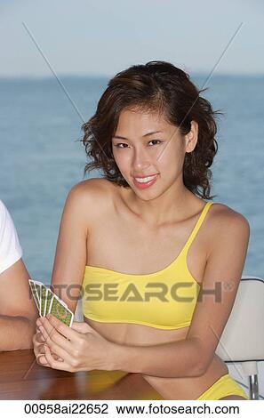 Stock Image - A young woman with playing cards and smiling at the camera. Fotosearch