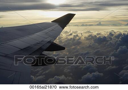Airplane flying over clouds, view of wing through plane window View Large Photo Image Stock Image - Airplane flying over clouds, view of wing through plane window. Fotosearch