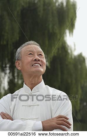 Stock Photograph - An old man crosses his arms and looks into the distance. Fotosearch