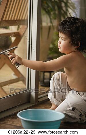 Stock Image - Baby boy cleaning the window. Fotosearch