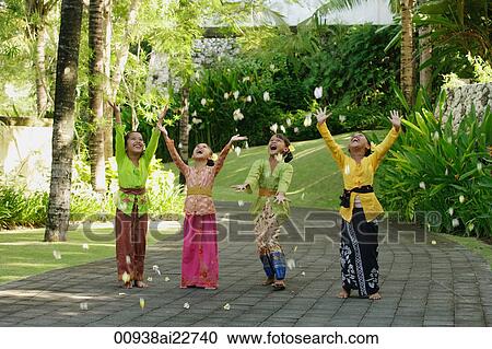 Stock Image - Balinese girls laughing and throwing flowers. Fotosearch