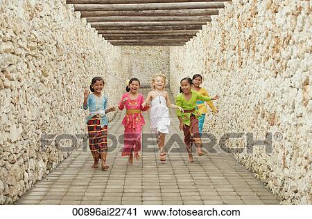 Stock Image - Balinese girls running with Caucasian girl. Fotosearch