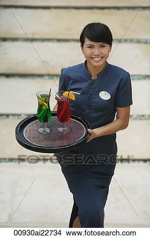 Picture - Balinese waitress carrying cocktails. Fotosearch