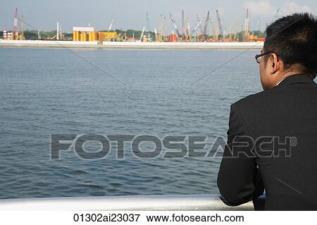 Businessman leaning on railing and looking into distance View Large Photo Image Stock Photo - Businessman leaning on railing and looking into distance. Fotosearch