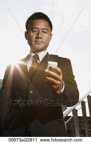 Businessman looking at mobile phone View Large Photo Image Stock Image - Businessman looking at mobile phone. Fotosearch