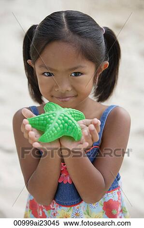 Stock Photography - Girl with starfish smiling at camera. Fotosearch