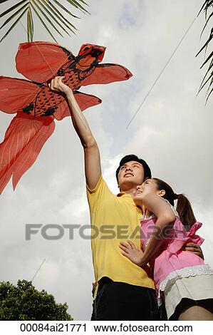 Man and woman flying kite in park View Large Photo Image Stock Image - Man and woman flying kite in park. Fotosearch