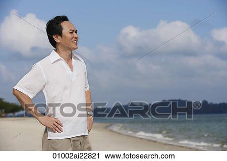 Stock Image - Man at the beach, looking into distance. Fotosearch