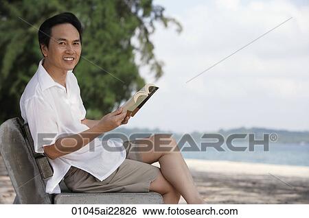 Man at the beach sitting on a bench, looking at camera View Large Photo Image Stock Photograph - Man at the beach sitting on a bench, looking at camera. Fotosearch