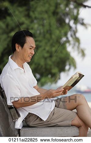 Man at the beach, sitting on a bench and reading a book View Large Photo Image Stock Photography - Man at the beach, sitting on a bench and reading a book. Fotosearch