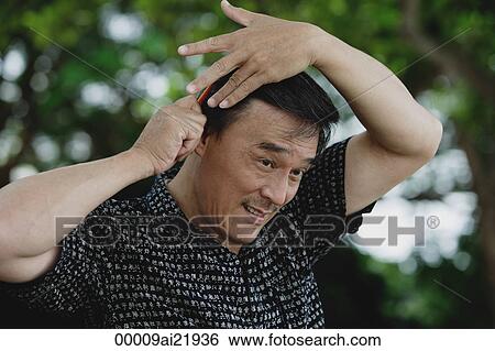 Man combing hair in park View Large Photo Image Stock Photograph - Man combing hair in park. Fotosearch