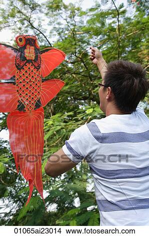 Picture - Man flying goldfish kite. Fotosearch