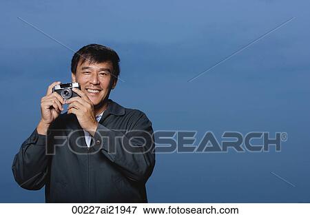 Man holding camera, smiling View Large Photo Image Stock Photo - Man holding camera, smiling. Fotosearch