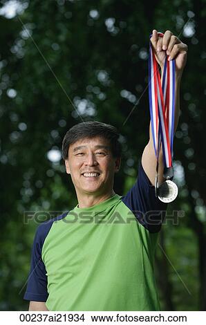 Picture - Man holding medals, winner, smiling. Fotosearch