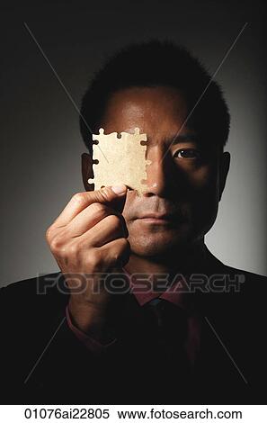 Stock Photography - Man holding up puzzle pieces. Fotosearch