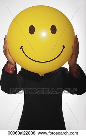 Stock Photo - Man holding up smiley face balloon. Fotosearch