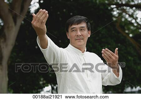 Stock Image - Man in park doing Tai Chi, martial arts. Fotosearch