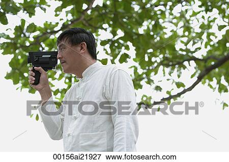 Man in park holding super 8 movie camera View Large Photo Image Stock Photo - Man in park holding super 8 movie camera. Fotosearch