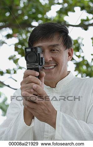Man in park using super 8 movie camera, looking at camera View Large Photo Image Stock Photo - Man in park using super 8 movie camera, looking at camera. Fotosearch