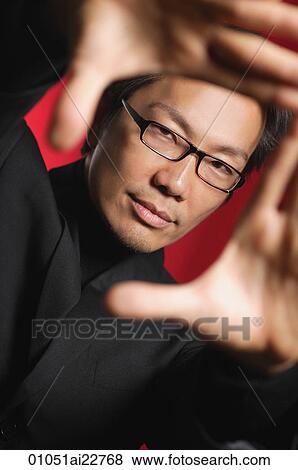 Stock Photo - Man looking at camera, making finger frame. Fotosearch