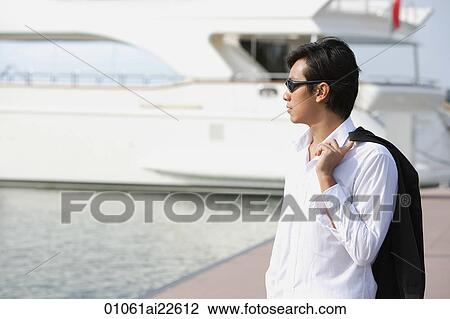 Stock Image - Man on pier, looking into distance. Fotosearch