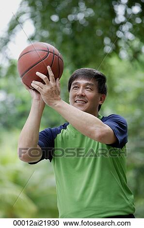 Stock Image - Man playing basketball in park. Fotosearch
