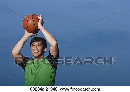 Stock Photo - Man playing basketball, throwing ball, smiling. Fotosearch