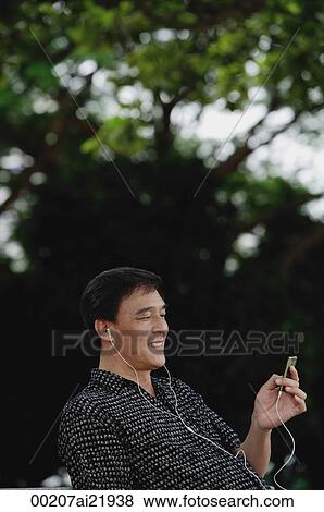 Man sitting in park, listening to music on MP3 player View Large Photo Image Stock Photo - Man sitting in park, listening to music on MP3 player. Fotosearch
