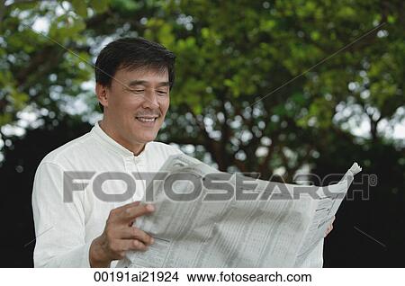 Man sitting in park reading newspaper View Large Photo Image Picture - Man sitting in park reading newspaper. Fotosearch