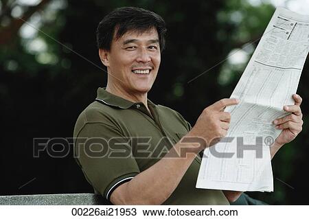 Man sitting on bench in park reading newspaper, smiling at camera View Large Photo Image Stock Image - Man sitting on bench in park reading newspaper, smiling at camera. Fotosearch