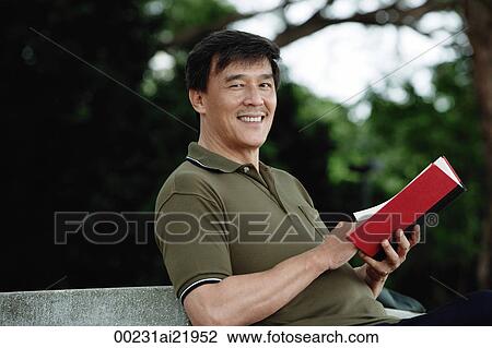 Man sitting on bench in park, reading, looking at camera smiling View Large Photo Image Stock Image - Man sitting on bench in park, reading, looking at camera smiling. Fotosearch