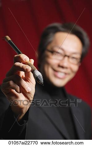 Man smiling at camera, holding a Chinese paint brush View Large Photo Image Stock Image - Man smiling at camera, holding a Chinese paint brush. Fotosearch