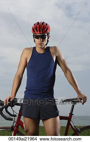 Man standing next to bike, taking break, looking at camera View Large Photo Image Picture - Man standing next to bike, taking break, looking at camera. Fotosearch