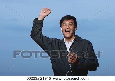 Man walking and listening to music on MP3 player, arm raised in air View Large Photo Image Stock Photography - Man walking and listening to music on MP3 player, arm raised in air. Fotosearch