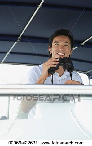 Stock Image - Man with binoculars, looking into distance. Fotosearch
