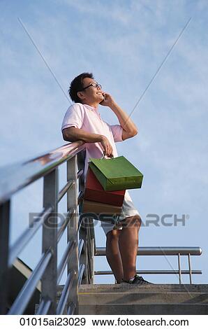 Man with shopping bags using mobile phone View Large Photo Image Stock Photo - Man with shopping bags using mobile phone. Fotosearch