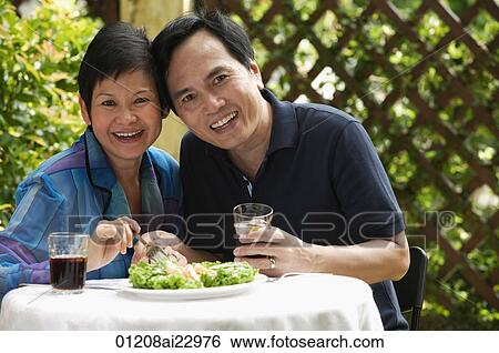 Stock Photograph - Mature couple at restaurant smiling at camera. Fotosearch