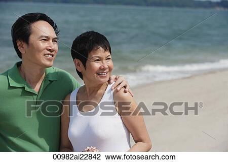 Mature couple at the beach looking into distance View Large Photo Image Stock Image - Mature couple at the beach looking into distance. Fotosearch
