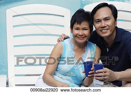 Mature couple by the pool smiling at camera View Large Photo Image Stock Image - Mature couple by the pool smiling at camera. Fotosearch