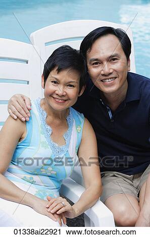 Mature couple by the pool smiling at camera View Large Photo Image Stock Image - Mature couple by the pool smiling at camera. Fotosearch