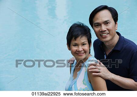 Mature couple by the pool smiling at camera View Large Photo Image Stock Photography - Mature couple by the pool smiling at camera. Fotosearch