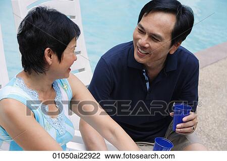 Mature couple in deck chairs by the pool View Large Photo Image Stock Image - Mature couple in deck chairs by the pool. Fotosearch