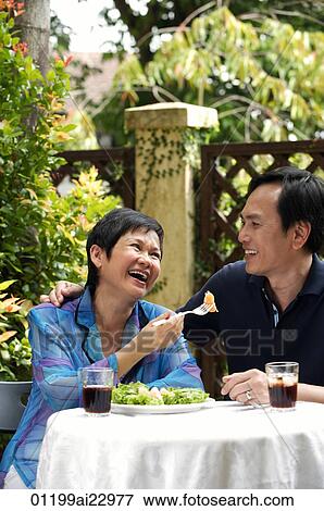 Stock Photo - Mature couple laughing while dining in restaurant. Fotosearch