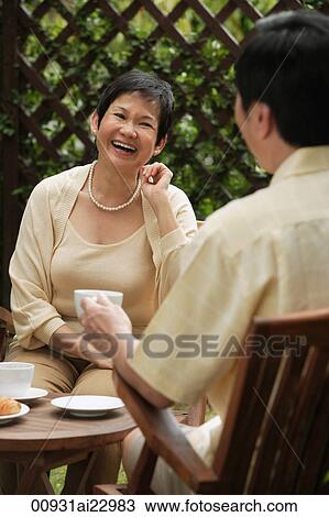 Mature couple laughing while having tea View Large Photo Image Stock Image - Mature couple laughing while having tea. Fotosearch