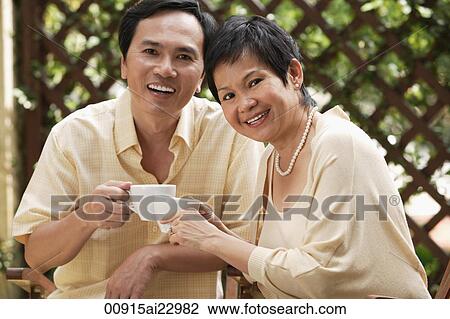Mature couple smiling at camera while having tea View Large Photo Image Stock Image - Mature couple smiling at camera while having tea. Fotosearch