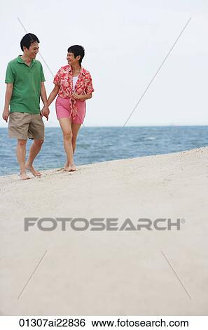 Stock Photograph - Mature couple walking at the beach. Fotosearch