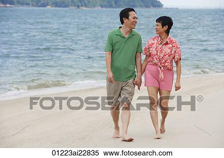 Stock Photography - Mature couple walking at the beach looking at each other. Fotosearch
